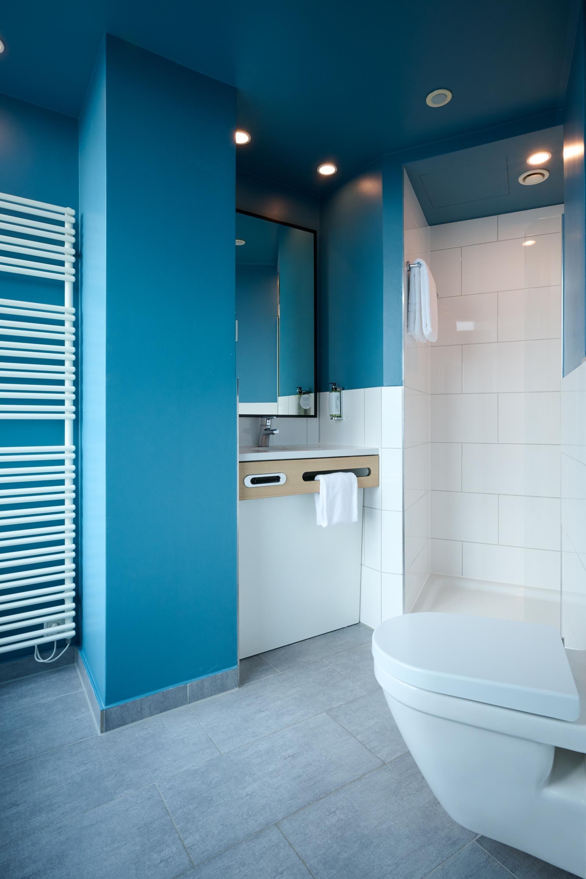Et moderne badeværelse med toilet, håndvask med spejl og bruseniche.