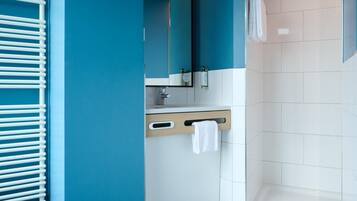 A modern bathroom with a white toilet, a sink with a mirror, and a shower area.