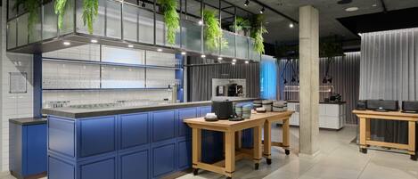 A modern kitchen with blue cabinetry, a central island, and hanging plants.