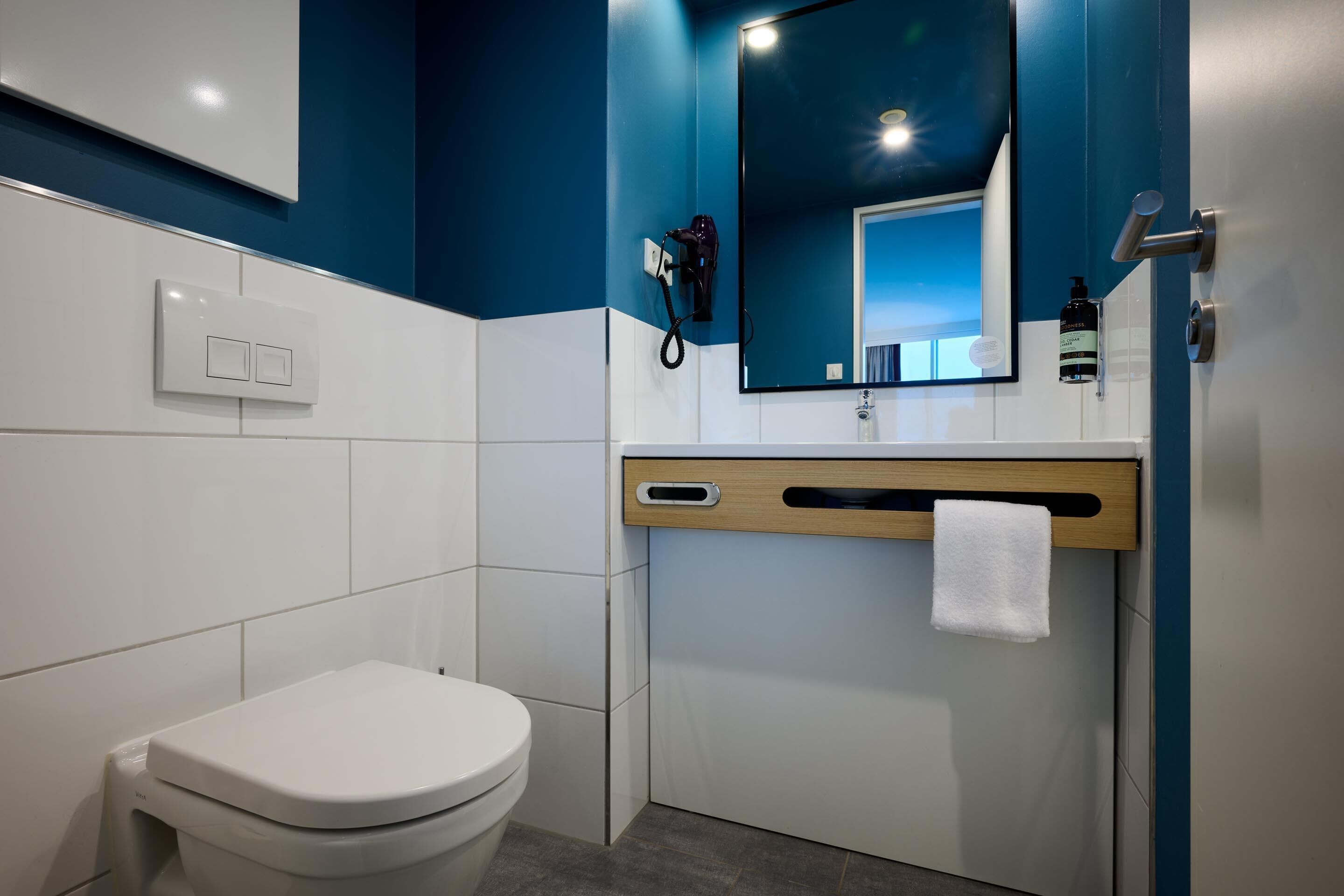 A modern bathroom with a white toilet, a mirror, and a towel rack.