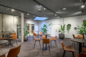Un interior moderno con varias zonas de estar, plantas grandes en macetas y un tragaluz.