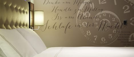 A hotel room with a large wall clock and motivational quote.