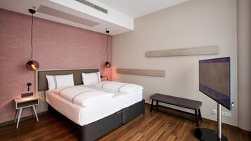A modern bedroom with a bed, bedside tables, a bench, a TV, and a wall-mounted shelf.