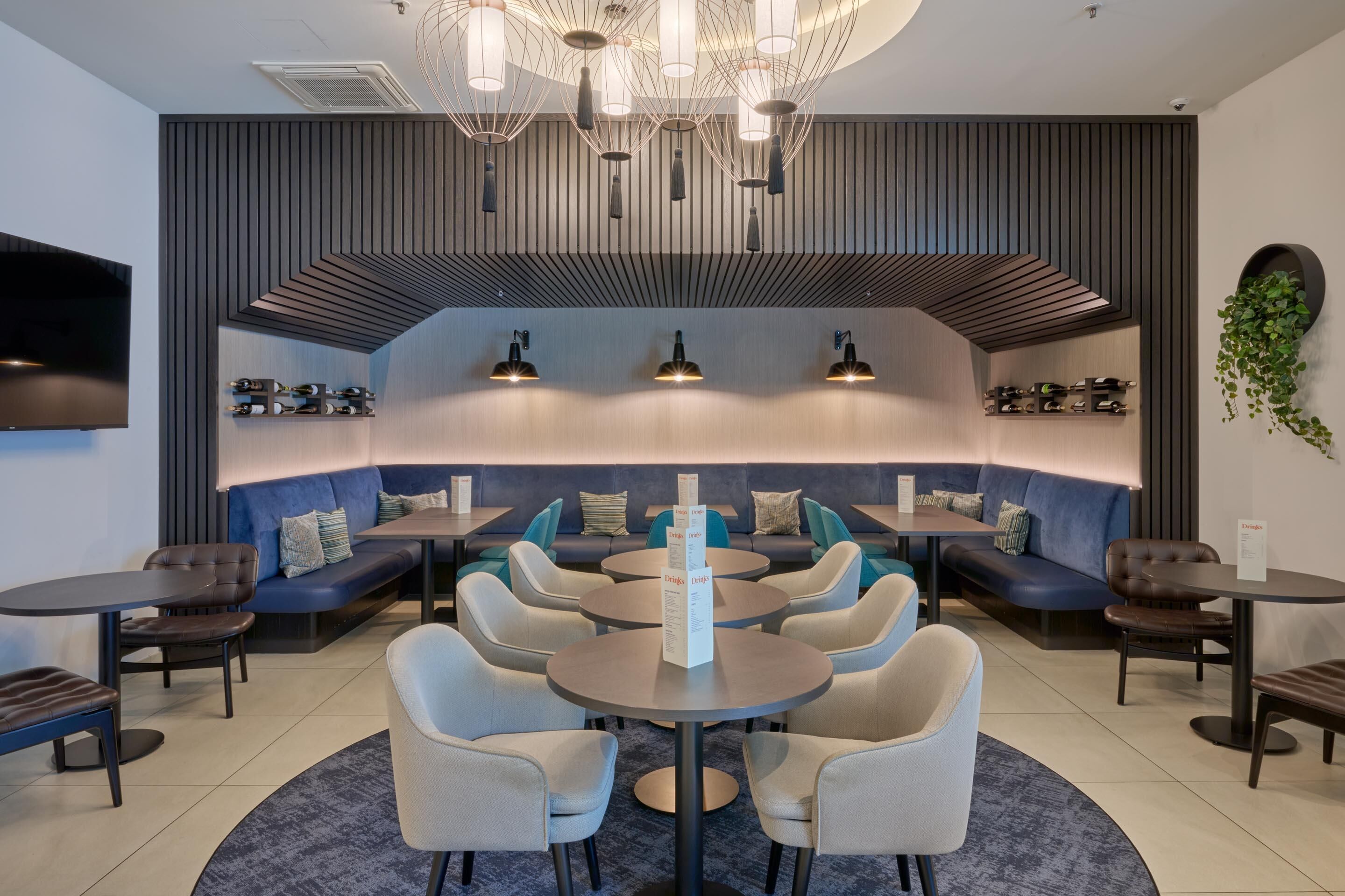 Un espace de détente moderne, doté de sièges, de tables et d’un design de plafond original.