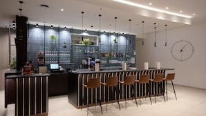 Un área de bar moderna con mostrador, taburetes y un reloj en la pared.