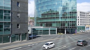 Un hotel moderno con fachada de vidrio curva, un logotipo destacado y un estacionamiento con automóviles.