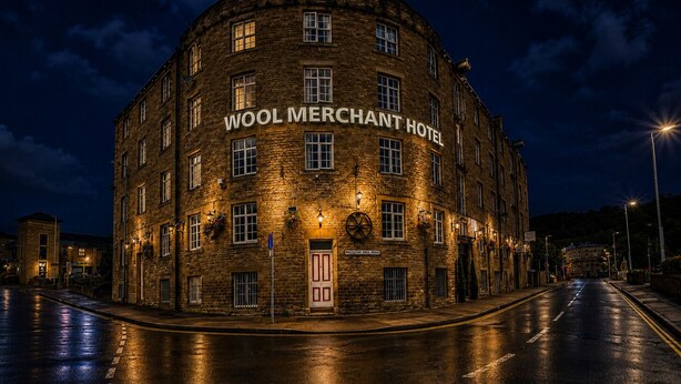 A historic building with the sign 'WOOL MERCHANT HOTEL' at night.