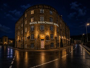 A historic building with the sign 'WOOL MERCHANT HOTEL' at night.