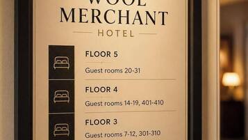 Een lijst in een lijstwerk voor Hotel Wool Merchant met gastenkamernummers en -locaties op de 3e, 4e en 5e verdieping, de Receptie Bar op de begane grond en een Ontbijtruimte op de benedenverdieping.