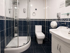 A bathroom with a glass-enclosed shower, a toilet, and a sink.