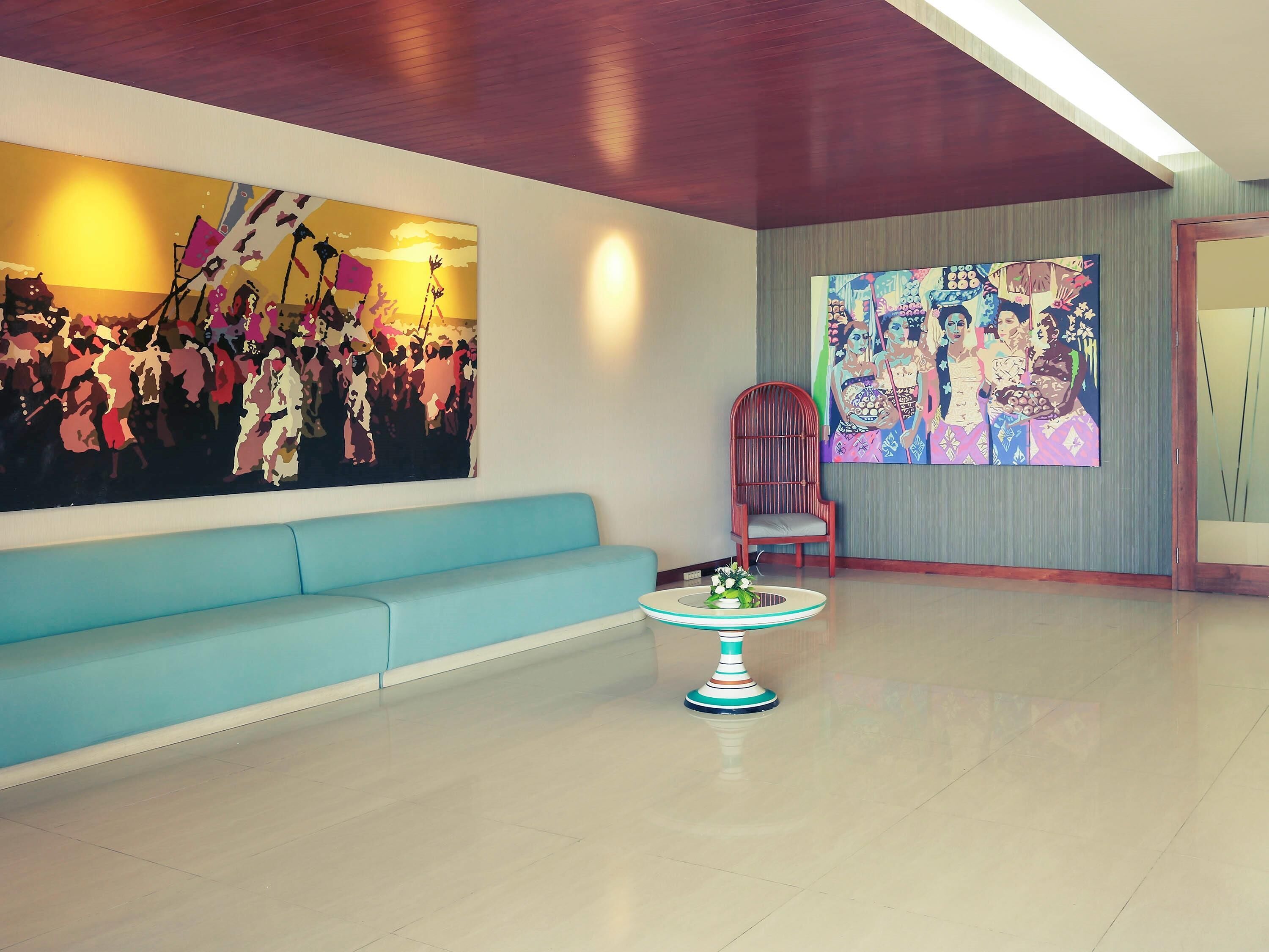 A modern living room with a light blue sofa, a round coffee table, and two large abstract paintings on the walls.