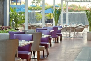 An outdoor seating area with tables and chairs, some with umbrellas. - Mercure Bali Nusa Dua (Nusa Dua)