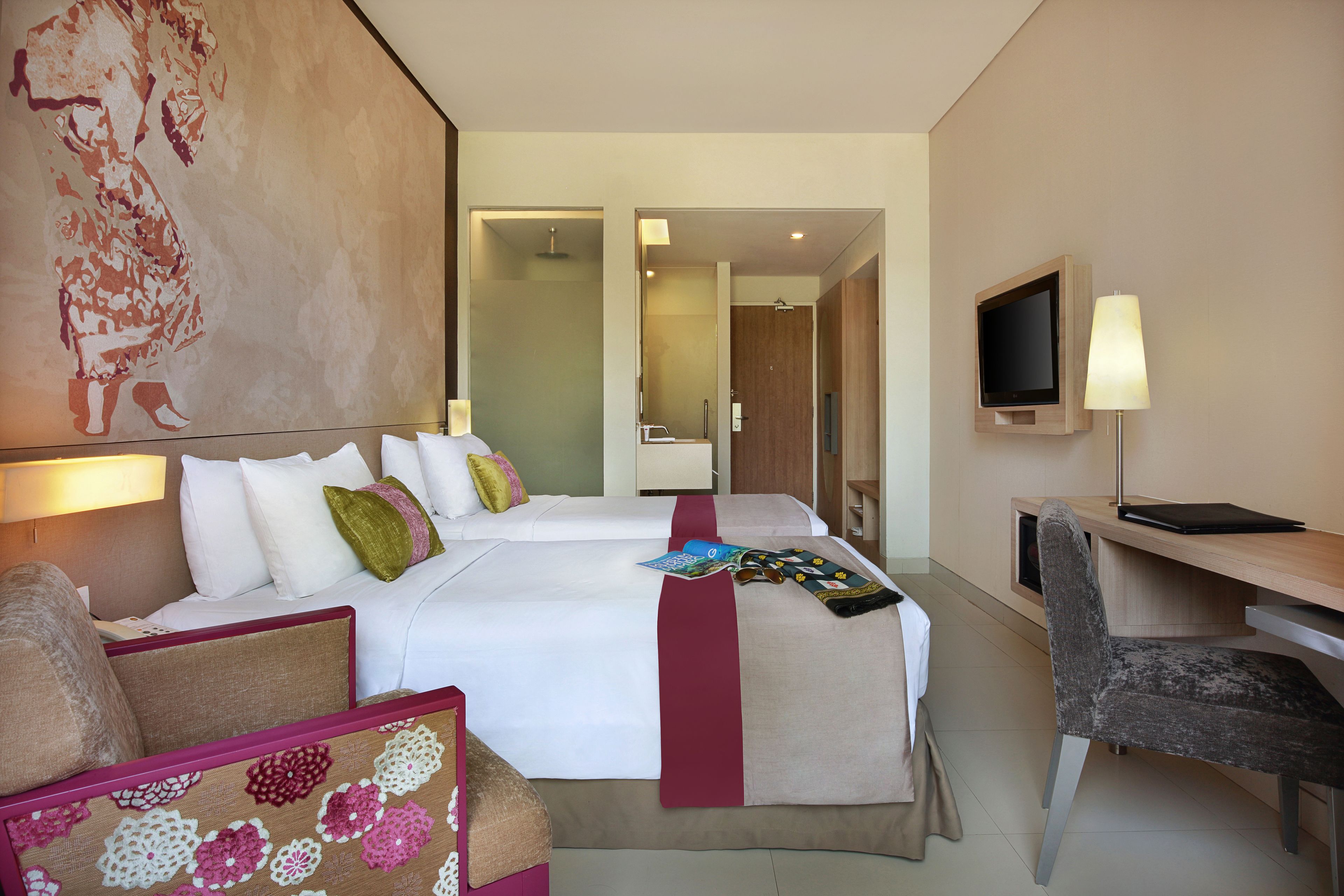 A hotel room with a large bed, a desk, a chair, a TV, and a painting on the wall.