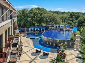 A hotel with a swimming pool, outdoor seating, and a view of the surrounding forest. - Mercure Bali Nusa Dua (Nusa Dua)