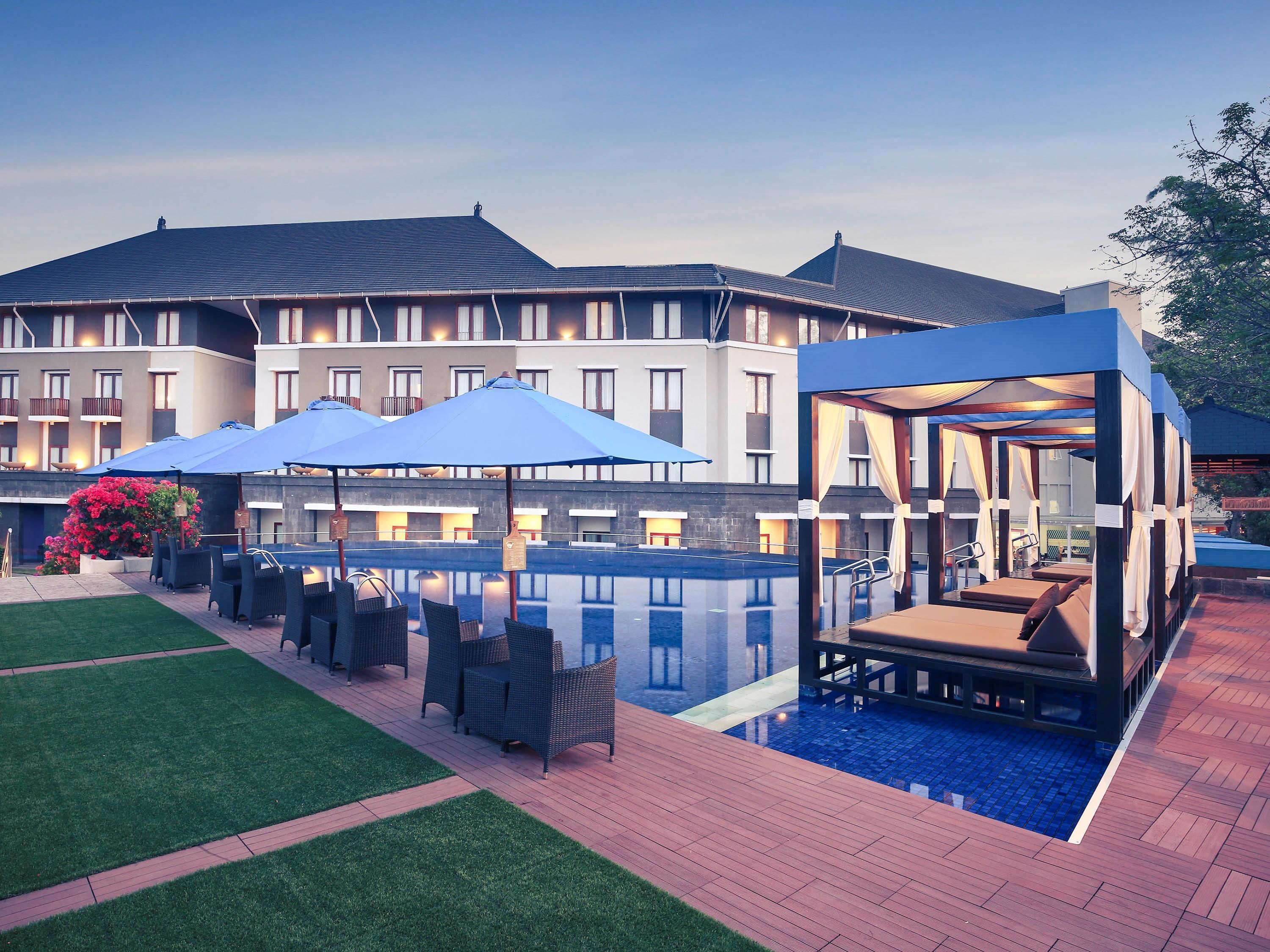 Un hotel con piscina, asientos exteriores y una zona de relajación cubierta.