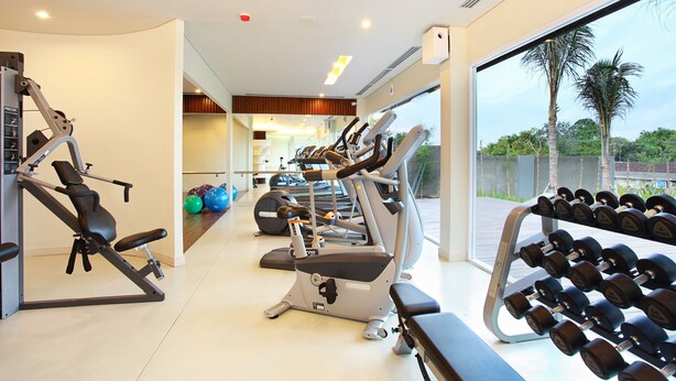 Ein Fitnessstudio mit Cardiogeräten, Kurzhanteln und Übungsbällen.