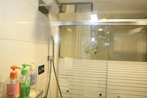 A shower with a glass enclosure, a hand dryer, and toiletries on the wall. - Cixi Hotel (Ningbo)