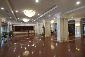 A spacious lobby with a reception desk, columns, and a polished floor.