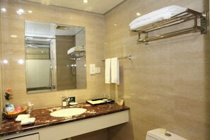 A bathroom with a marble sink, a large mirror, a towel rack, and a toilet.