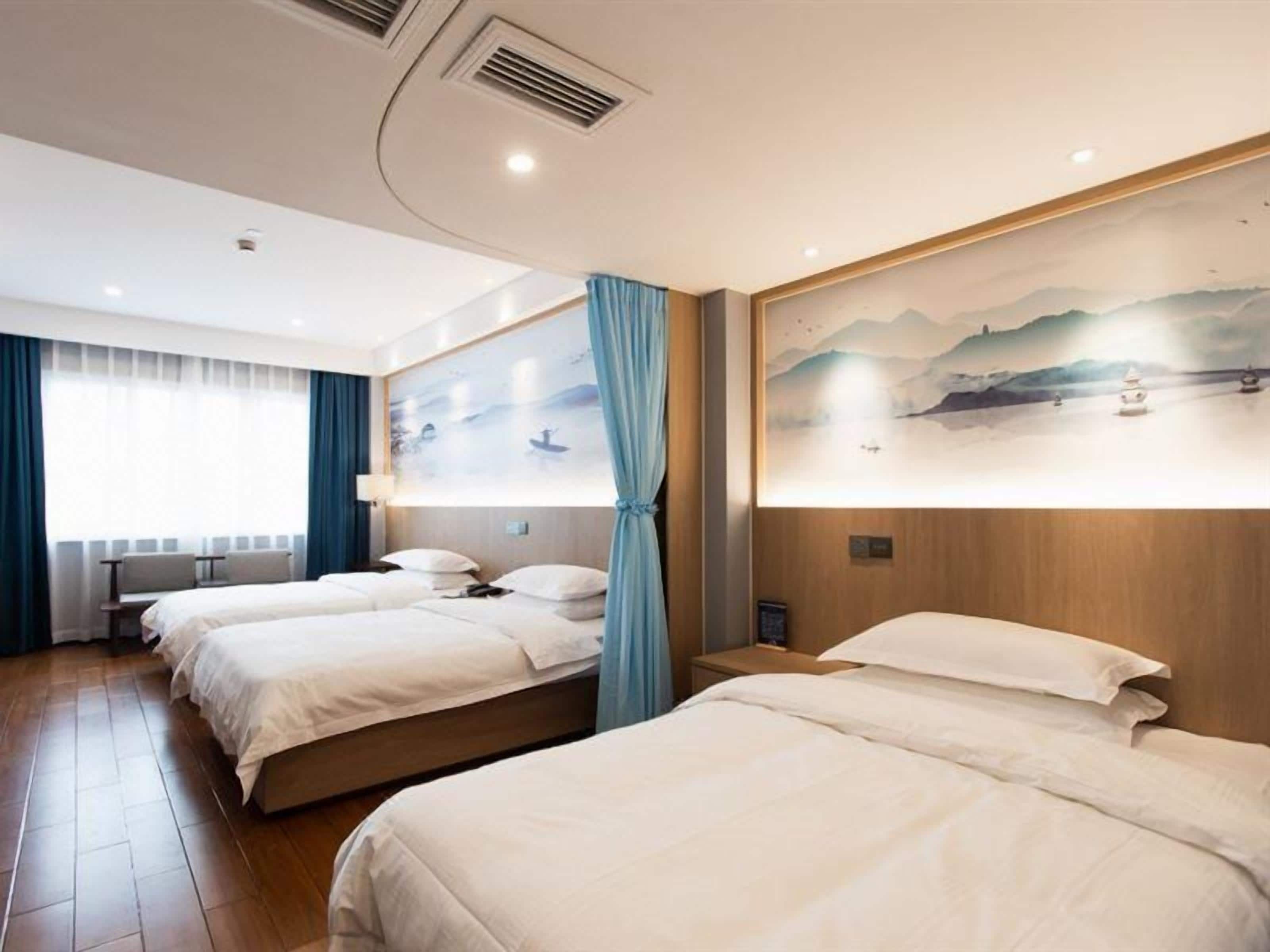 Habitación de hotel con dos camas, un cuadro grande en la pared y una ventana con cortinas.