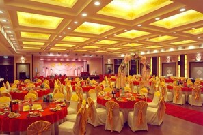 Une salle de banquet avec des tables rondes, des chaises et une scène.