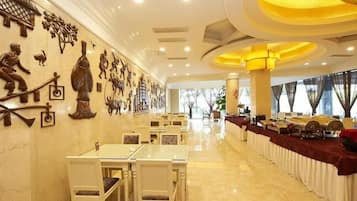 Un'area ristorazione in hotel con tavoli e sedie, un lungo buffet e decorazioni alle pareti.