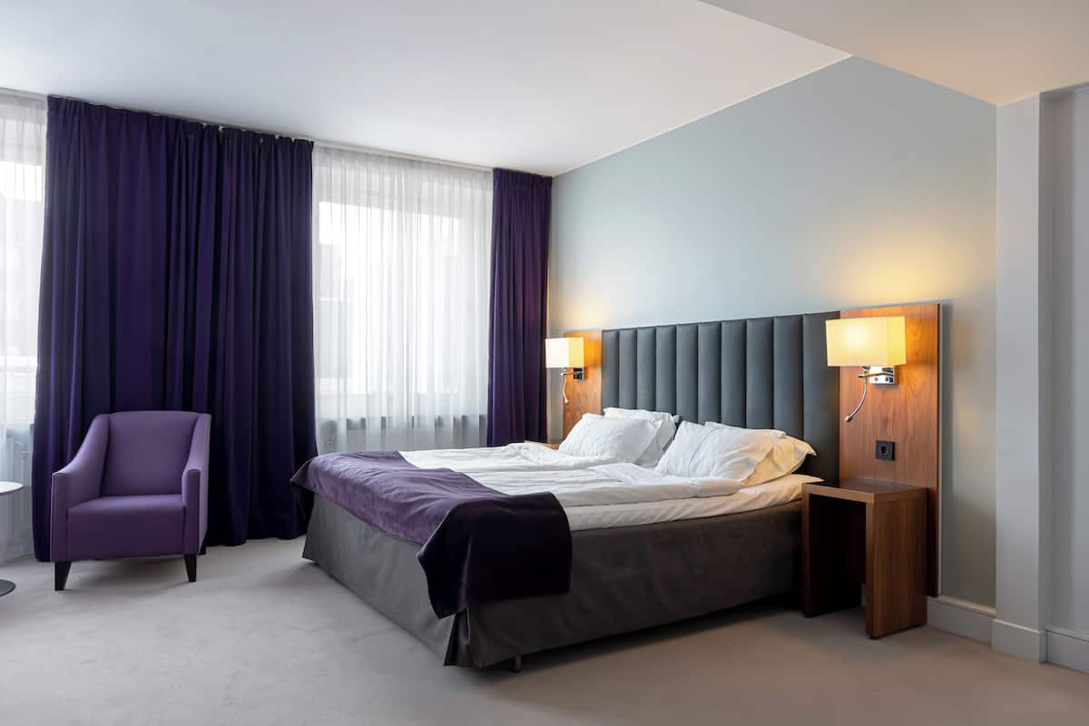 Ein modernes Hotelzimmer mit Bett, Stuhl, Nachttisch und Lampe.