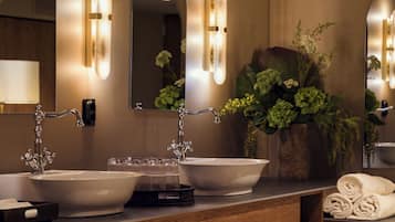 Une salle de bain moderne avec deux lavabos, un miroir et un vase de fleurs.