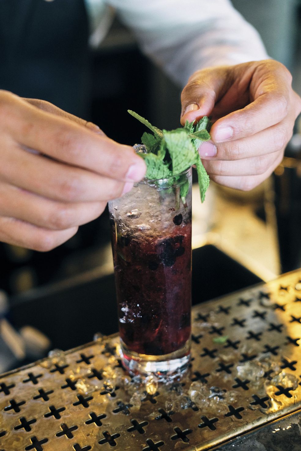 A person garnishing a drink with mint leaves.
