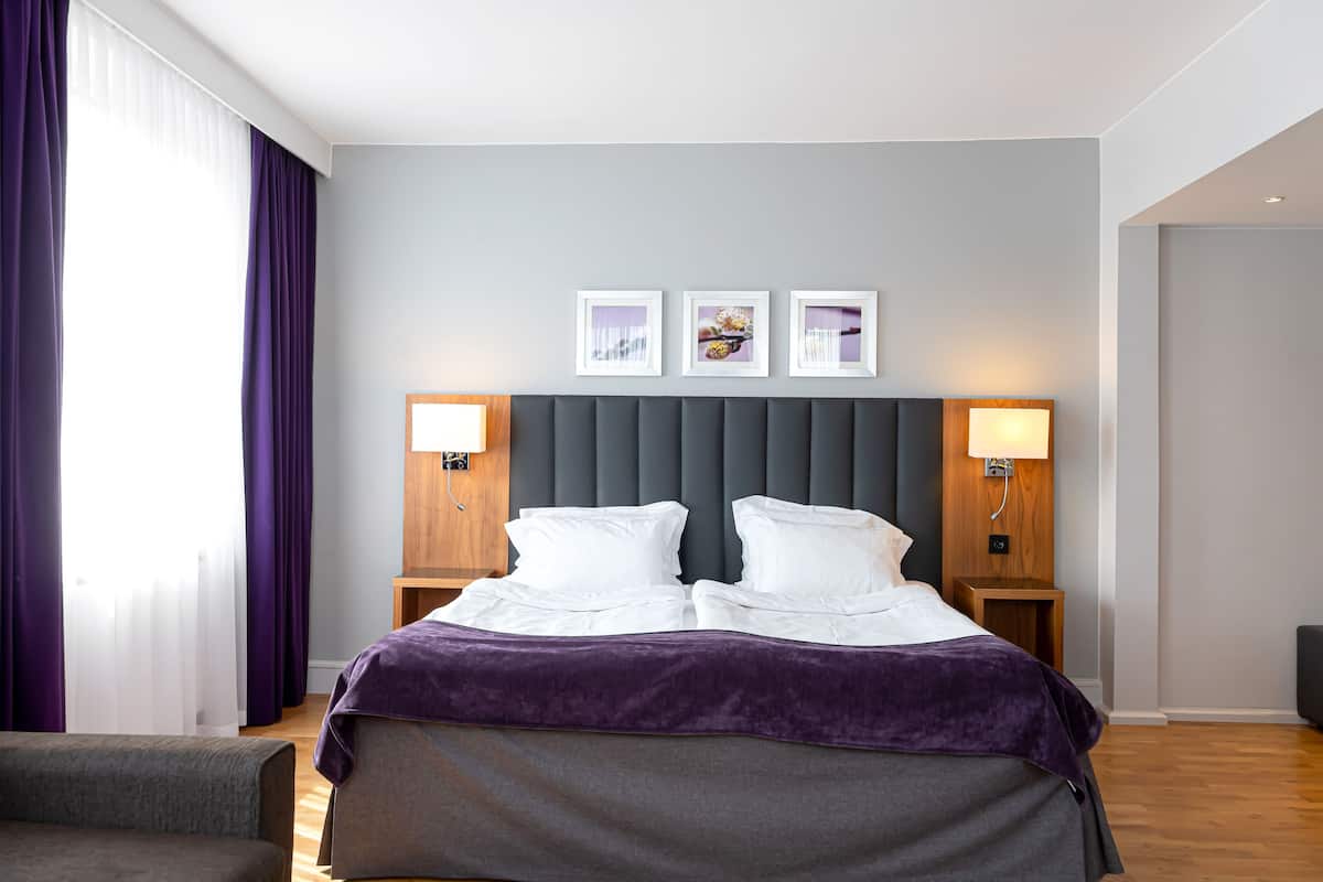Ein Hotelzimmer mit einem großen Bett, zwei Nachttischen, einer Kopfteil und drei gerahmten Bildern an der Wand.