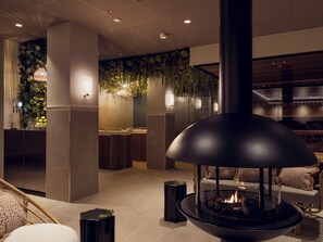 Een modern interieur met een open haard, zithoek en een wand begroeid met groen.