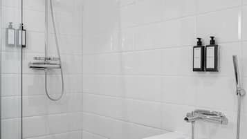 Un baño moderno con cabina de ducha de vidrio, una bañera independiente y dos botellas de champú en la pared.