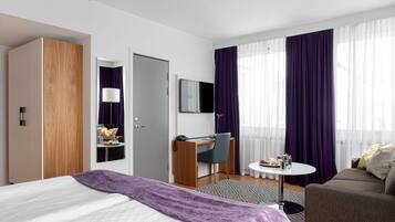 Una habitación de hotel moderna con cama, escritorio, silla, sofá y televisor.