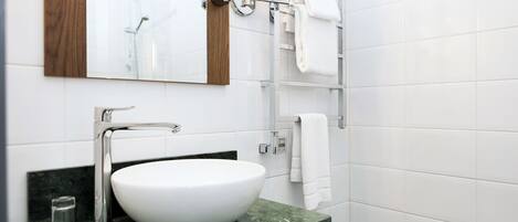 A modern bathroom with a white sink, a wooden-framed mirror, and a glass shower enclosure.
