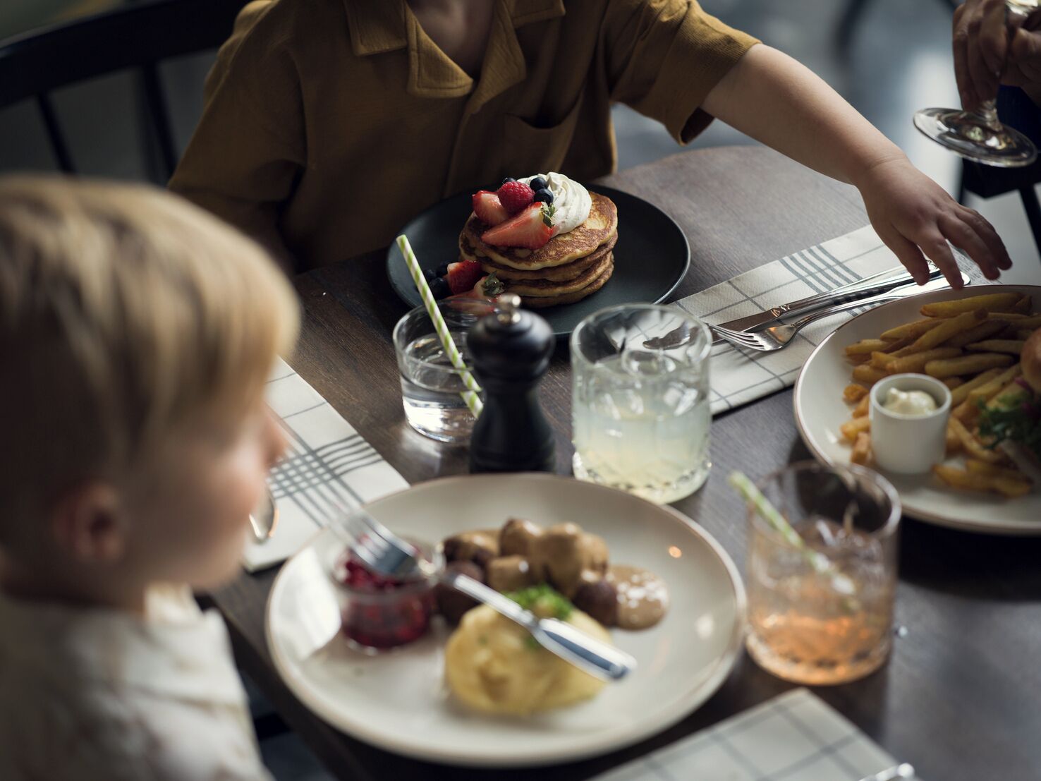 A dining table with plates of food, a glass of water, and a glass of a beverage.