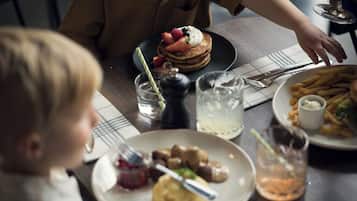 A dining table with plates of food, a glass of water, and a glass of a beverage.
