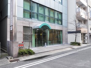 A modern building with a glass facade, a green awning with the hotel's name, and a clear entrance. - Kobe City Gardens Hotel (Kobe)