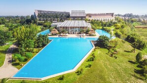 A large swimming pool with a modern building in the background. - InterContinental Heilong Lake by IHG (Meishan)