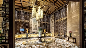 A lobby with traditional Chinese architectural elements, including intricate wooden lattice screens and a central pillar. - InterContinental Heilong Lake by IHG (Meishan)