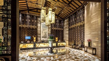 Un vestíbulo con elementos arquitectónicos tradicionales chinos, como elaboradas celosías de madera y un pilar central.