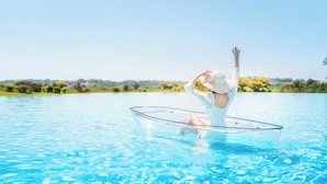 A person in a white outfit and hat, performing a yoga pose in a clear blue pool. - InterContinental Heilong Lake by IHG (Meishan)