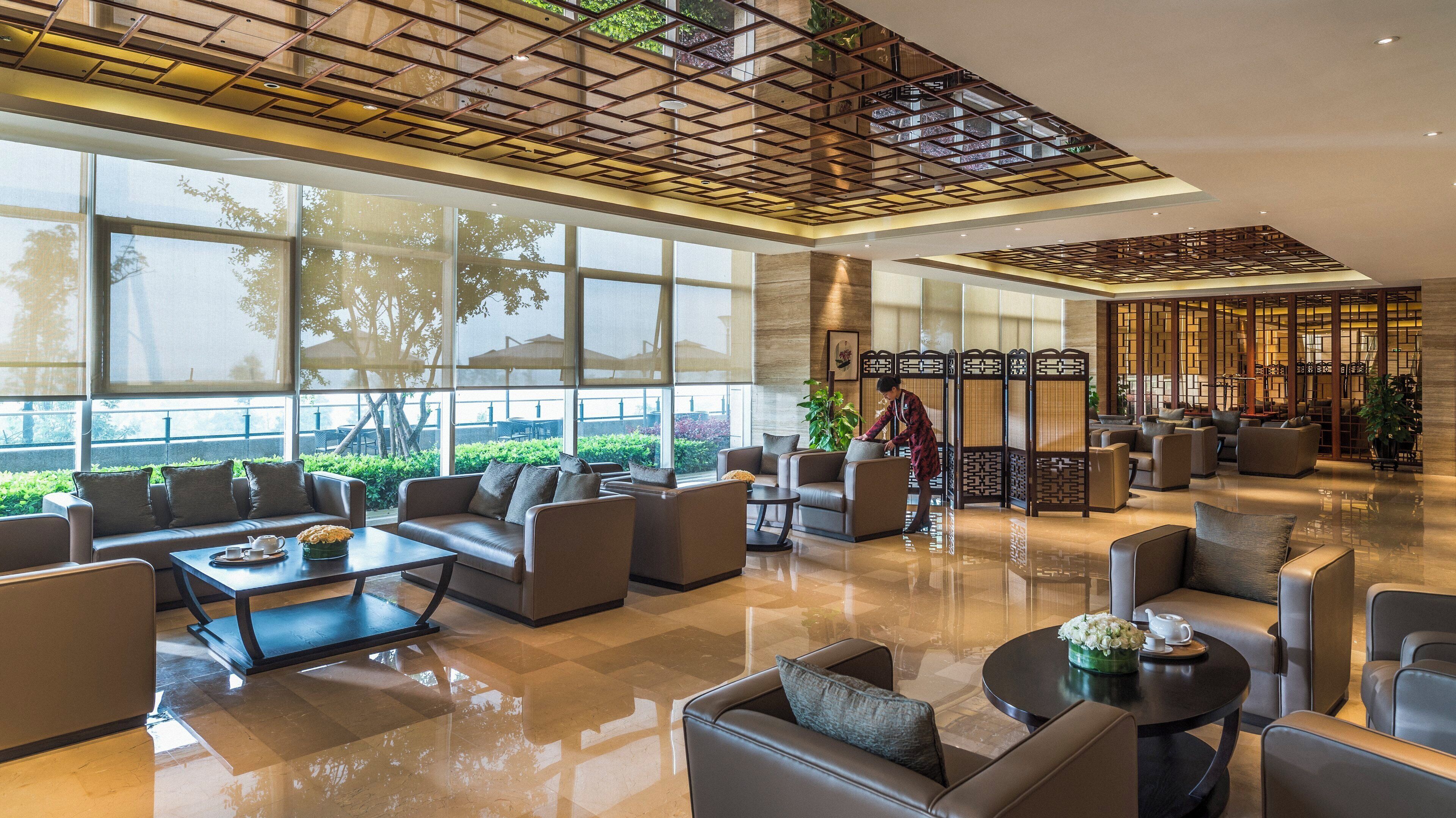 A spacious lobby with leather sofas, a coffee table, and a reception area with a decorative screen.