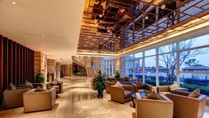 A spacious lobby with a modern design, featuring a central staircase, comfortable seating areas, and large windows offering views of the outdoors. - InterContinental Heilong Lake by IHG (Meishan)