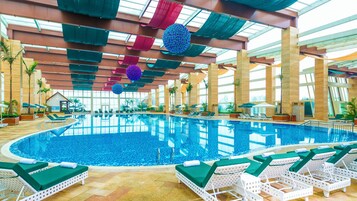Una piscina interior con sillas de descanso y sombrillas.