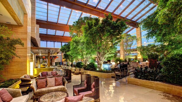 A spacious indoor lobby with a high ceiling, large windows, and lush greenery. - InterContinental Heilong Lake by IHG (Meishan)