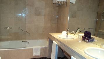 A bathroom with a bathtub, two sinks, a mirror, and a towel rack.