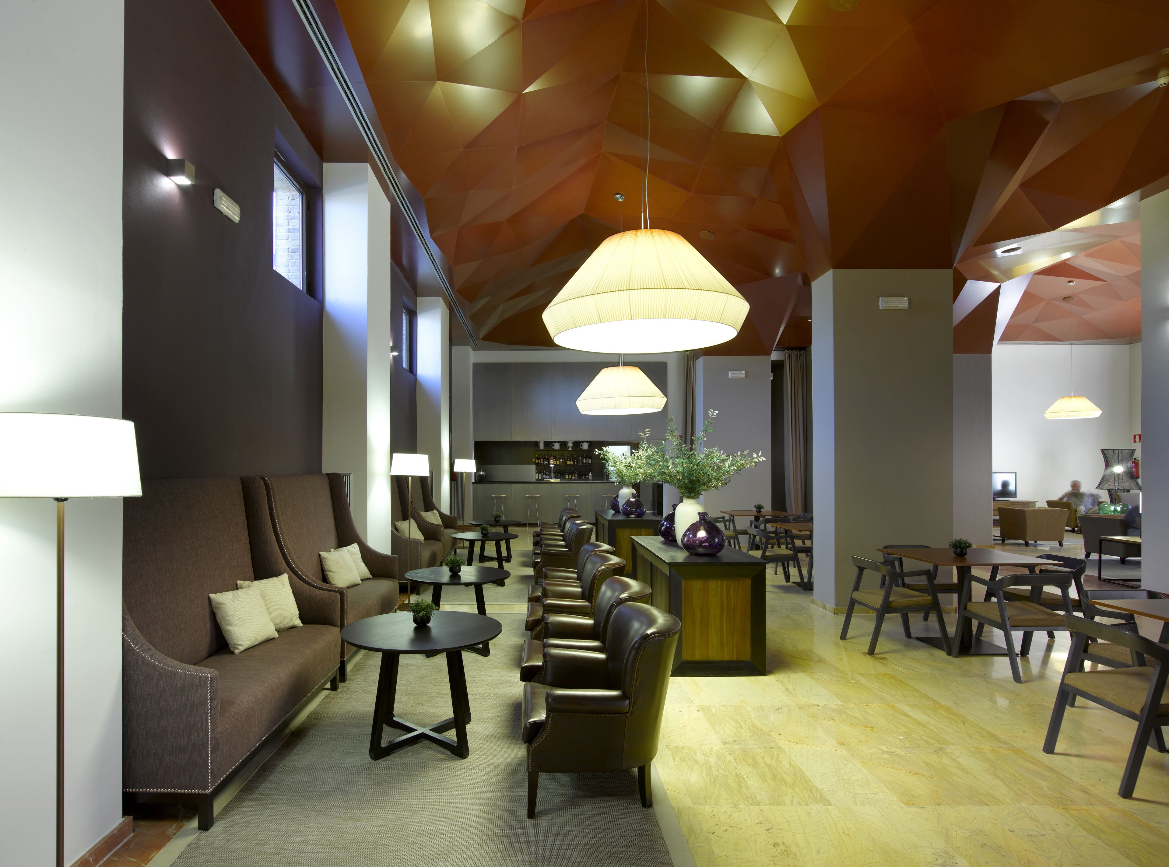 A modern hotel lobby with a seating area, a bar, and a dining space.