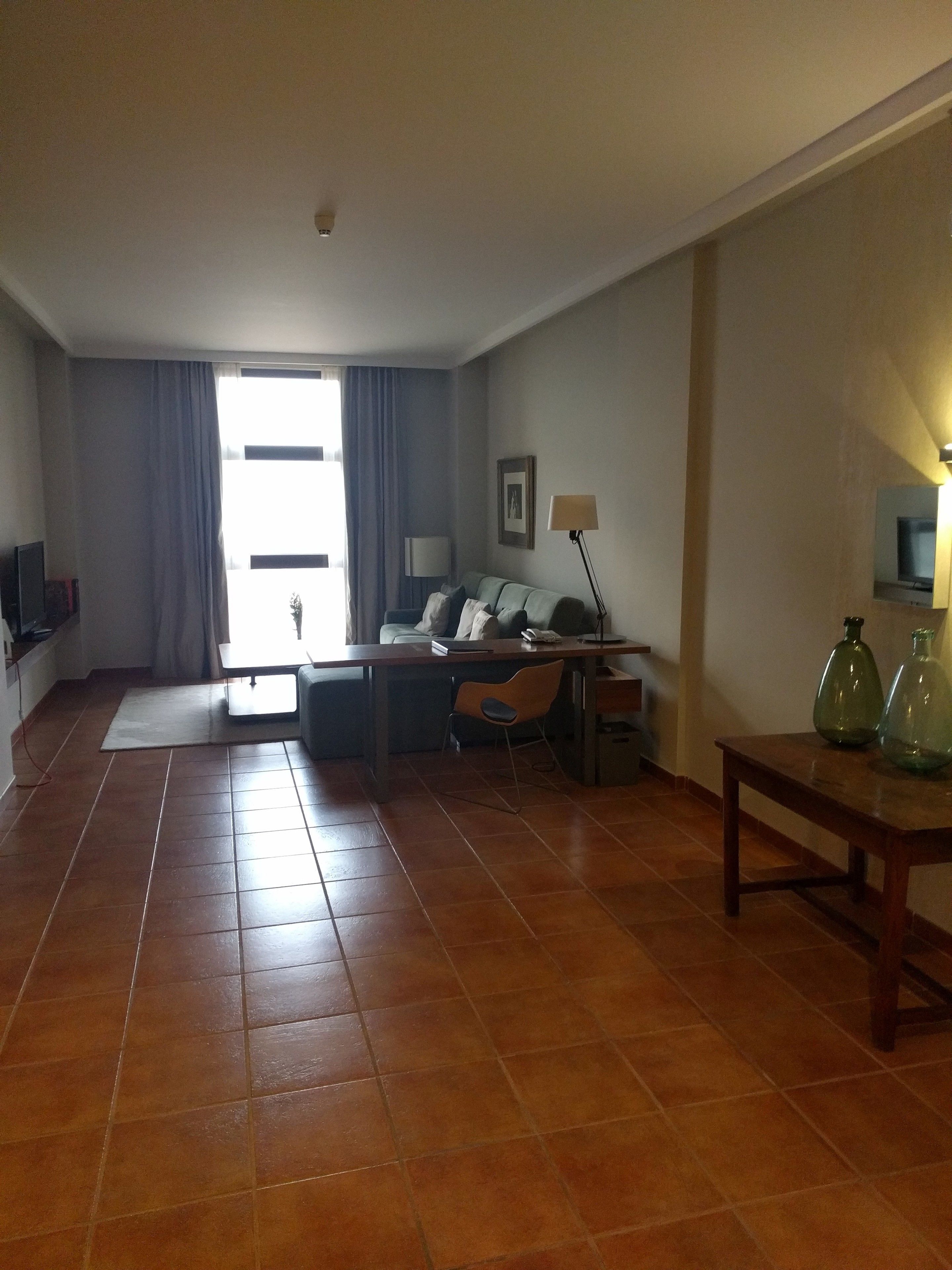 A spacious living room with a sofa, a dining table, and a TV.