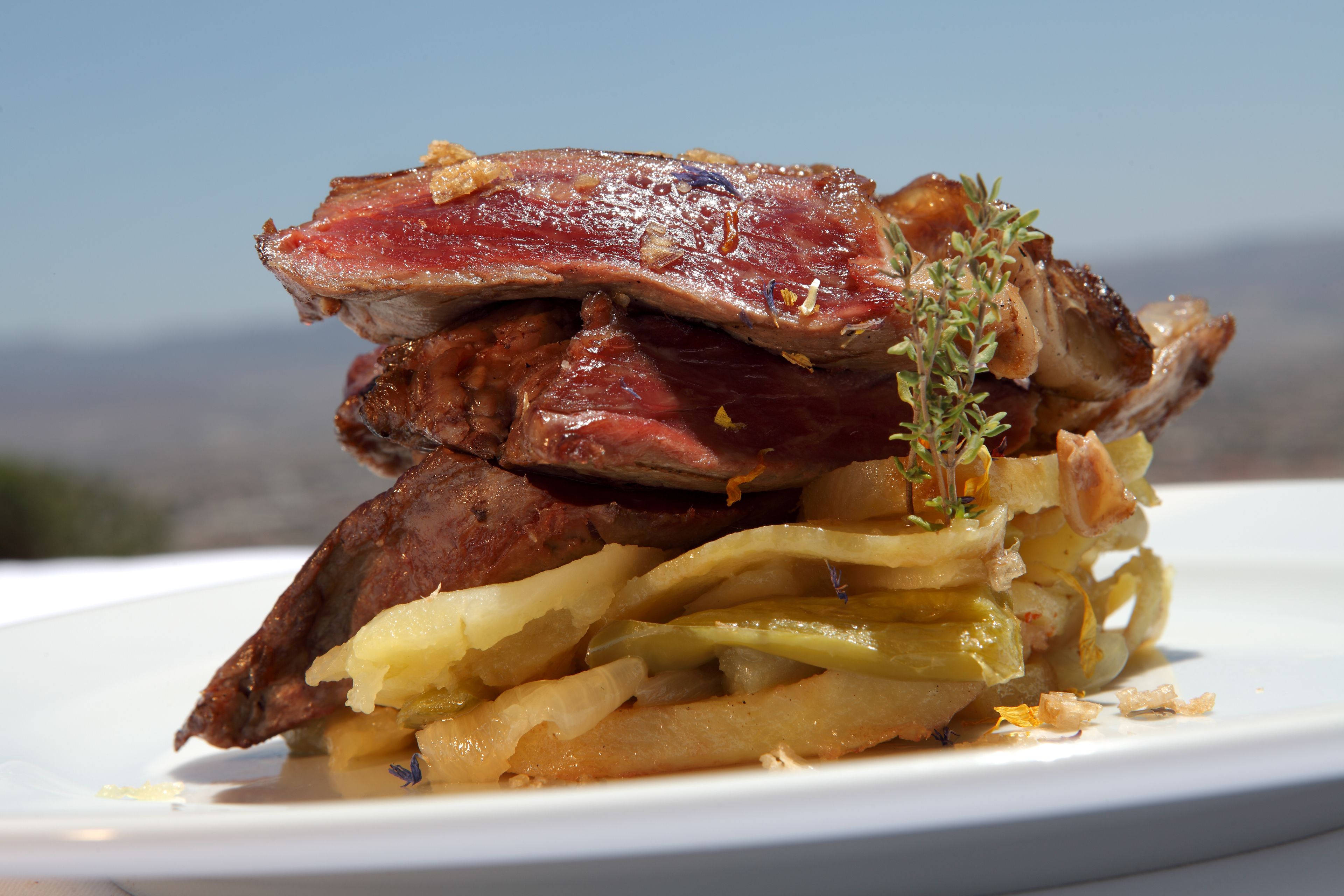 Un plato de comida con bistec y cebollas.