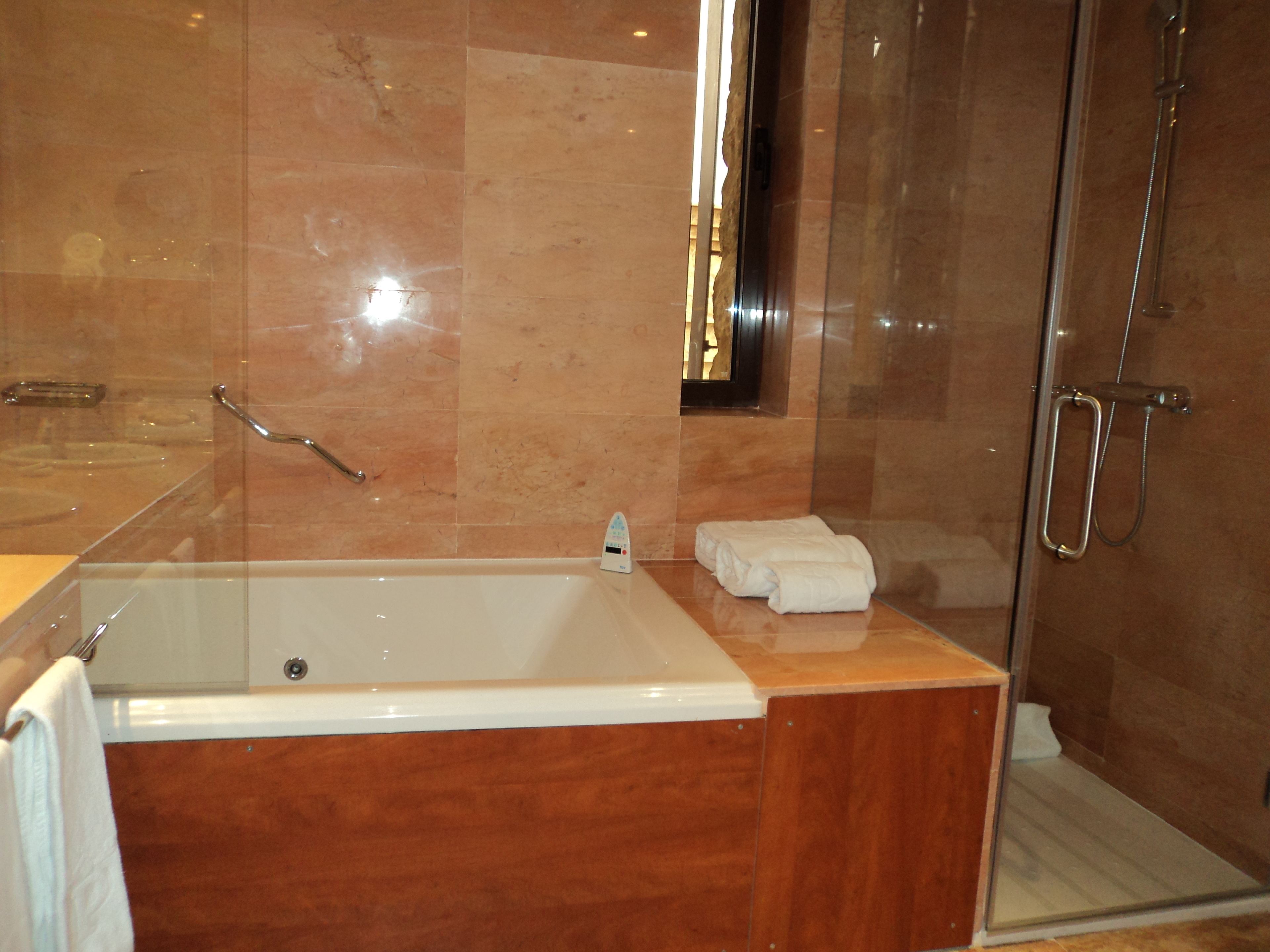 A modern bathroom with a large bathtub, a glass-enclosed shower, and a wooden vanity.
